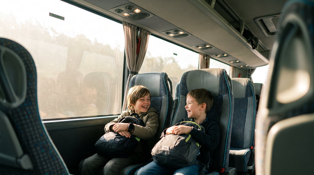 Deux enfants rient ensemble dans l'autocar au départ d'une classe de découverte